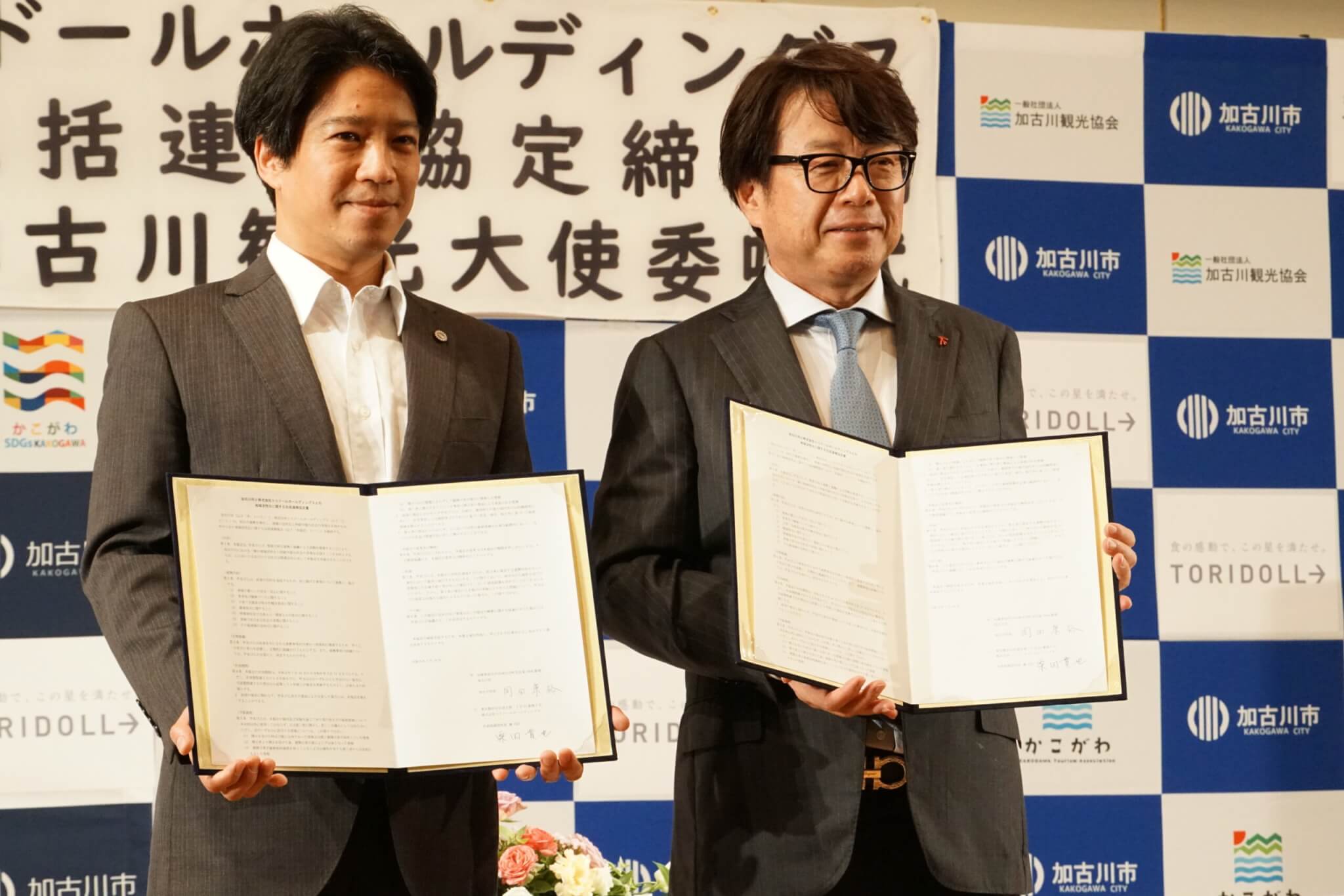 包括連携協定の締結のサインを見せる岡田康裕加古川市長と粟田貴也トリドールホールディングス社長兼CEO